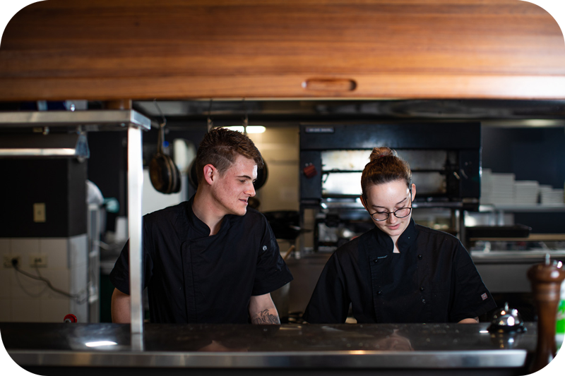 Apprentice and employer cooking in commercial kitchen