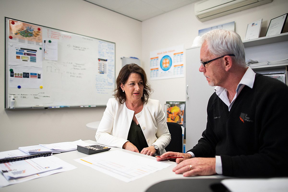 Two administration workers discussing documents in an office setting