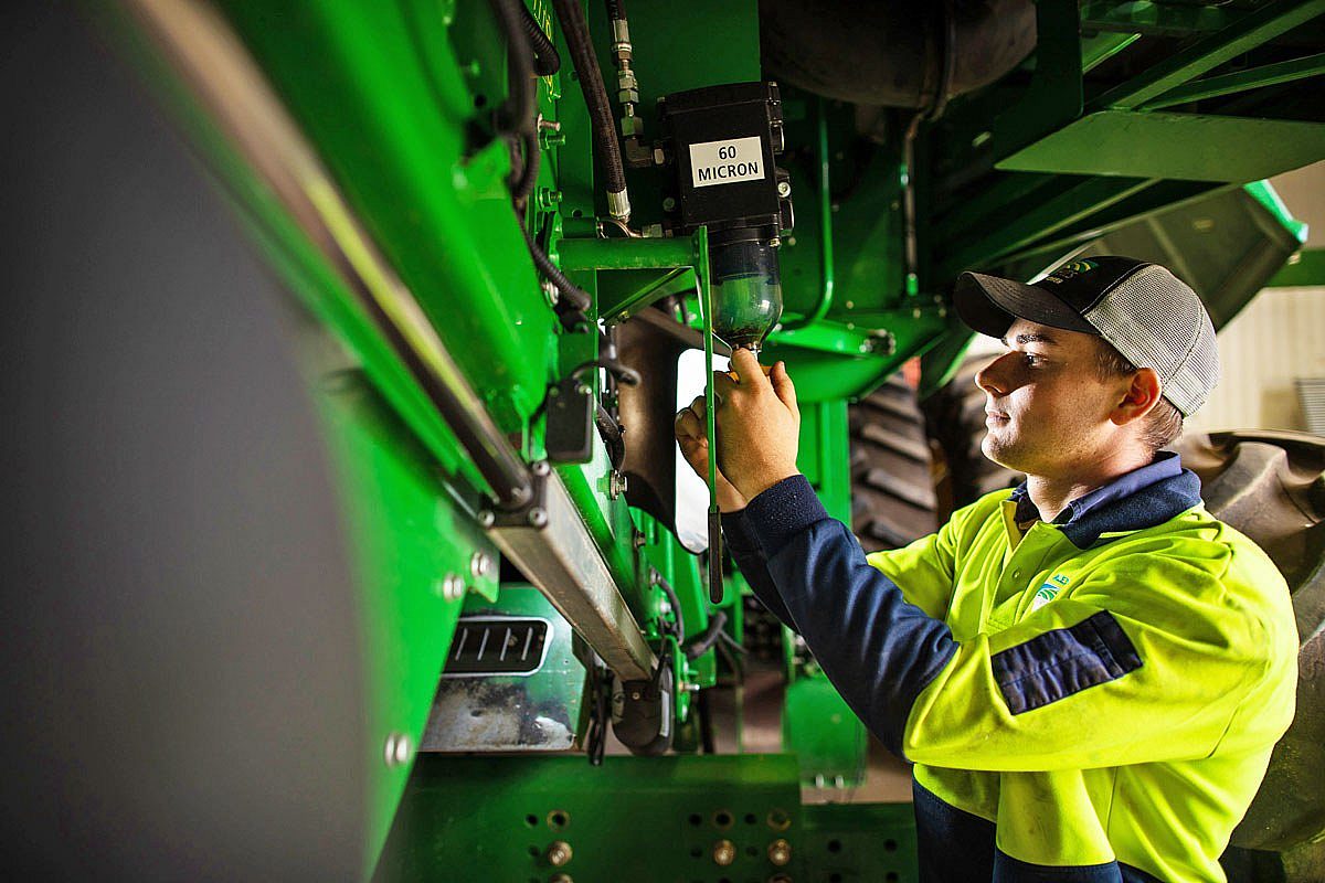 Young male farming apprentice working on heavy machinery