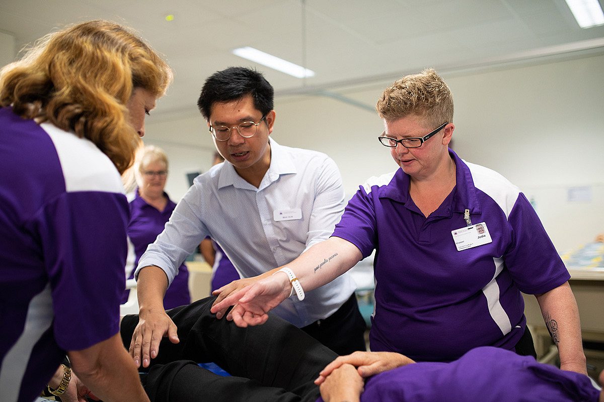 Nursing students training with a dummy in a healthcare setting