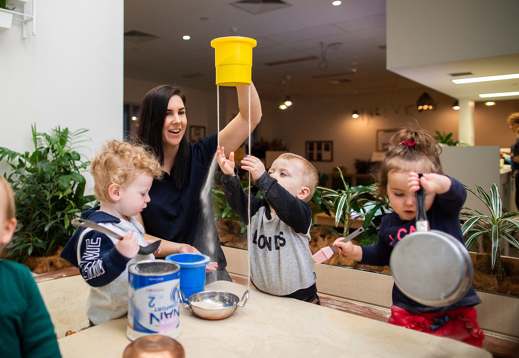 Child care worker playing with three young children in a childcare setting
